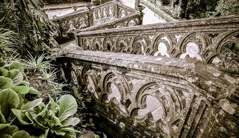 Balaustradas de pedra ornamentadas e vegetação nos jardins do Parque de Monserrate, em Sintra