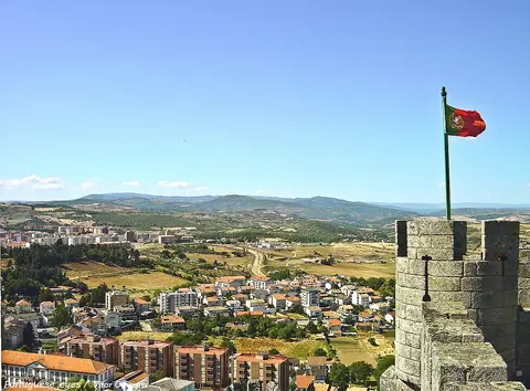 Ameias do Castelo de Bragança com bandeira de Portugal e vista sobre a cidade e serras