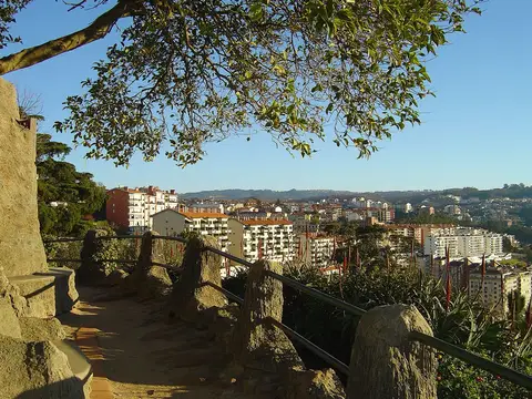 Miradouro do Penedo da Saudade, em Coimbra, com caminho de terra, guarda metálica e vista sobre a cidade