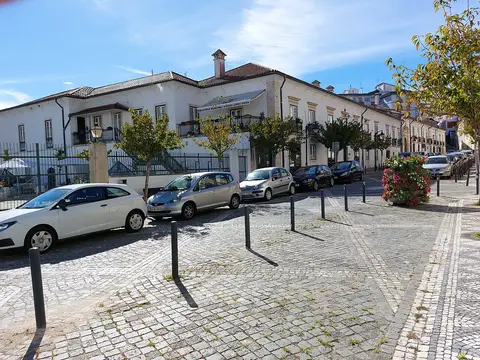Edifício branco de dois pisos da Biblioteca Municipal Afonso Lopes Vieira, com carros estacionados em frente