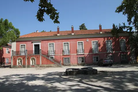 Fachada rosa do palacete da Quinta dos Lagares d'El-Rei com escadaria dupla e pátio arborizado