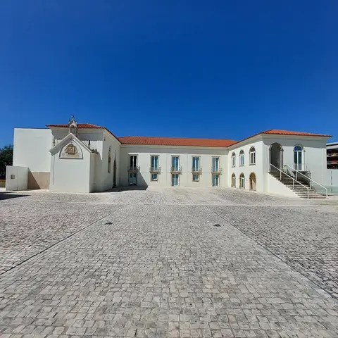 Edifício branco com telhado vermelho do Museu POROS em Condeixa-a-Nova, visto do largo calcetado