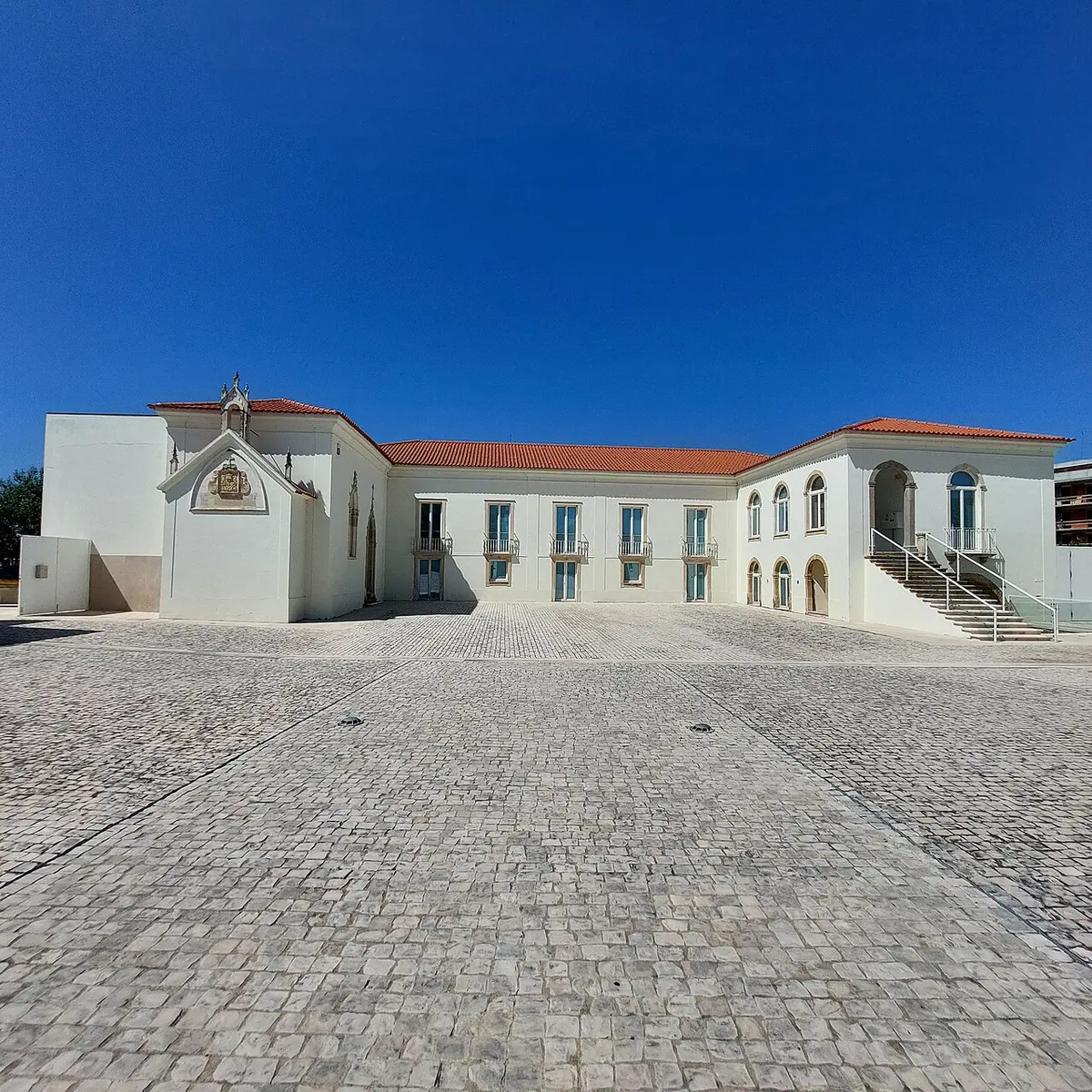 Edifício branco com telhado vermelho do Museu POROS em Condeixa-a-Nova, visto do largo calcetado