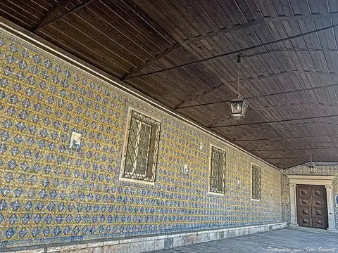 Galeria coberta com paredes revestidas de azulejos azuis e amarelos e tecto de madeira