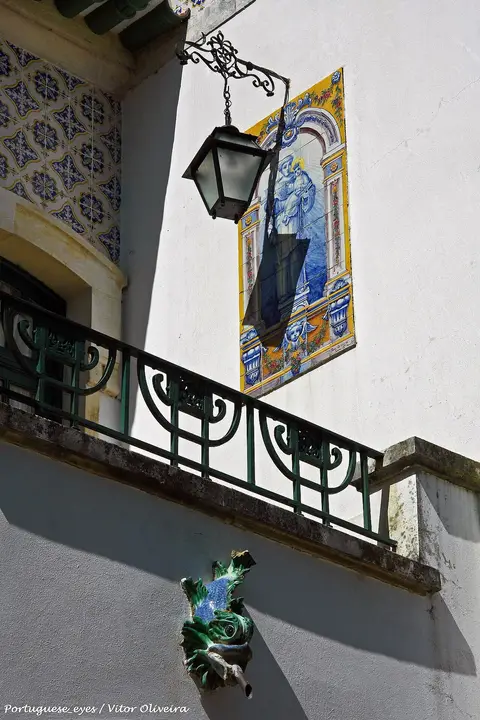 Pormenor da fachada da Casa-Museu de Egas Moniz com painel de azulejos, lanterna de ferro e varanda verde