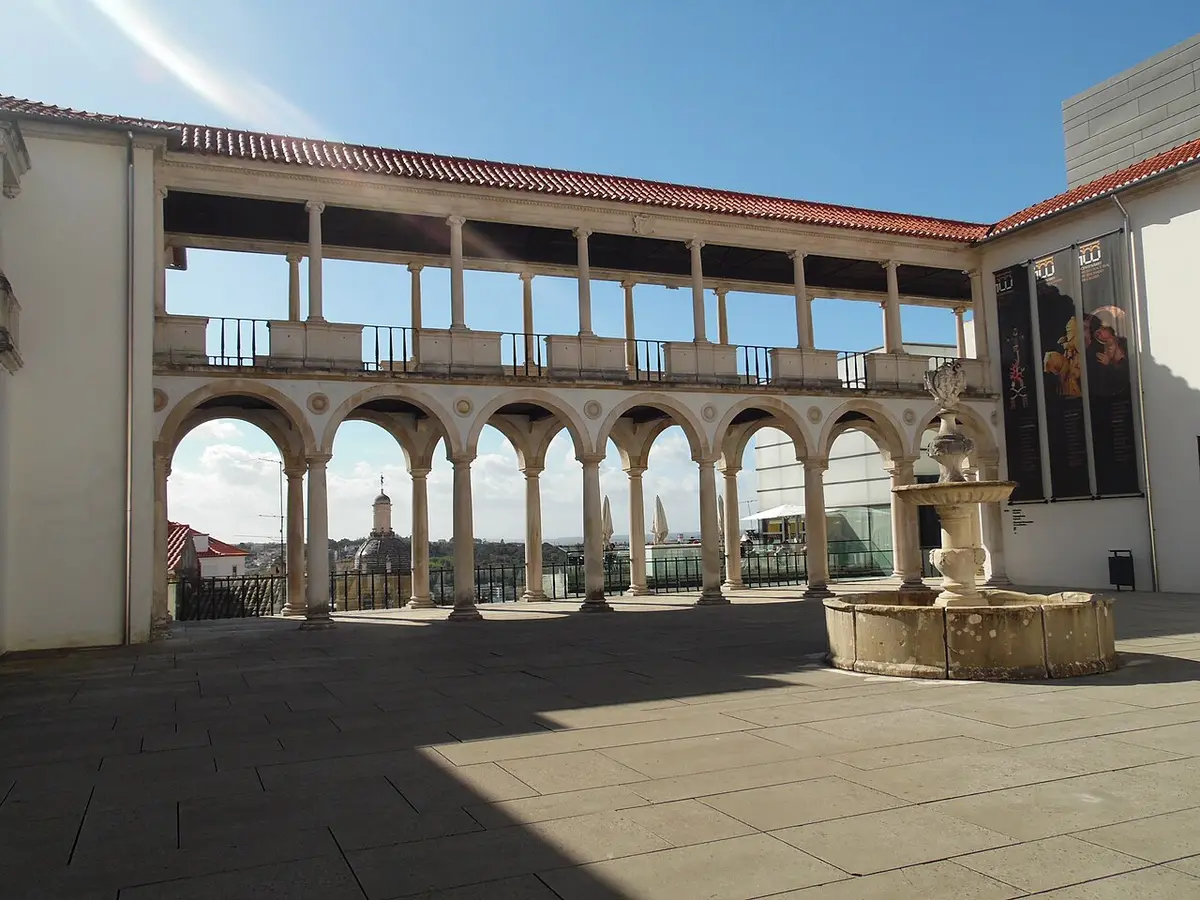 Pátio do Museu Machado de Castro em Coimbra, com loggia de arcos e fonte de pedra.