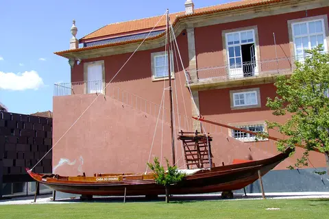 Barco rabelo exposto no relvado junto ao edifício vermelho do Museu do Douro, no Peso da Régua