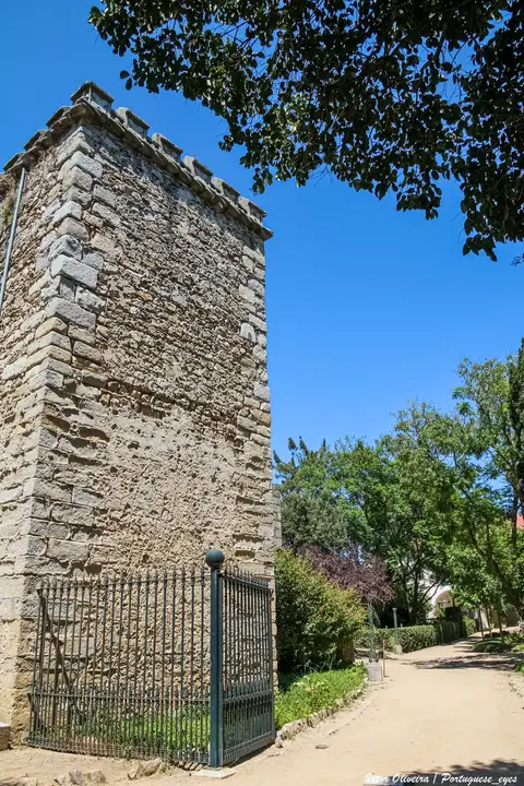 Torre de pedra com ameias junto a caminho arborizado no Jardim Público de Évora