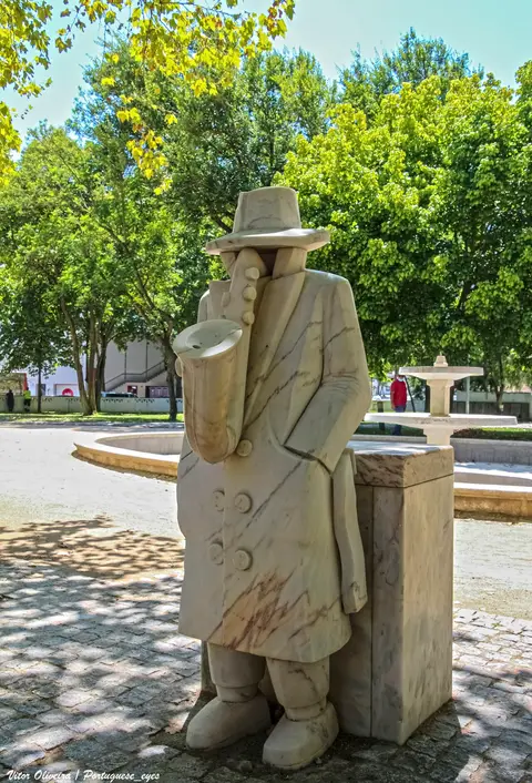 Escultura em mármore de músico com saxofone junto a um repuxo no Jardim Público de Évora