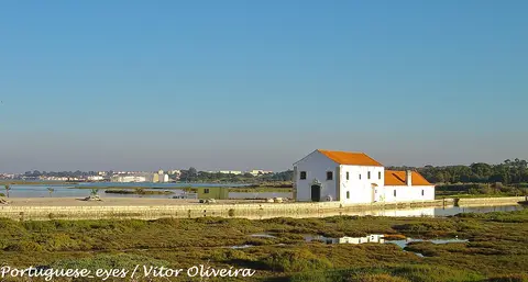 Moinho de maré de Corroios, edifício branco de telhado vermelho junto ao sapal do estuário