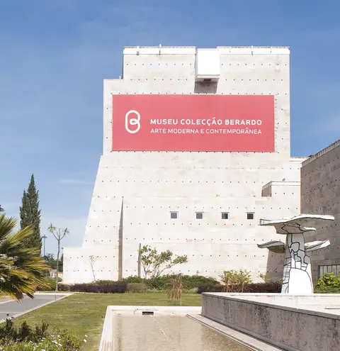 Fachada em pedra do Museu Colecção Berardo, no CCB, com faixa vermelha e escultura no jardim