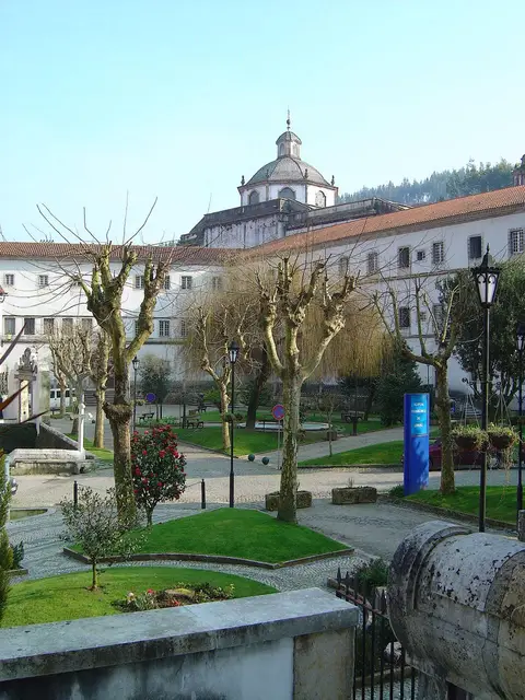 Mosteiro de Lorvão visto do jardim, com cúpula da igreja e árvores podadas em primeiro plano