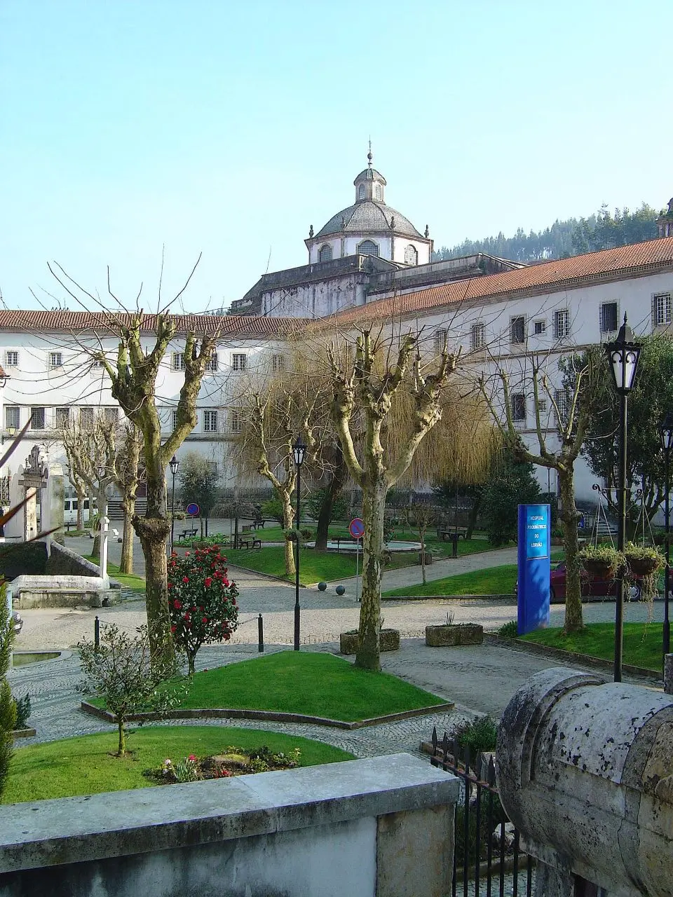 Mosteiro de Lorvão visto do jardim, com cúpula da igreja e árvores podadas em primeiro plano