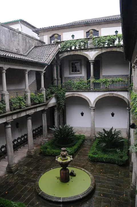 Pátio interior do Museu dos Biscainhos com arcadas, azulejos, canteiros e fonte circular.