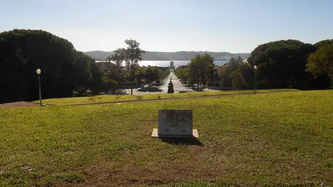 Relvado do Jardim Ducla Soares com placa de pedra e vista sobre a avenida até à Torre de Belém