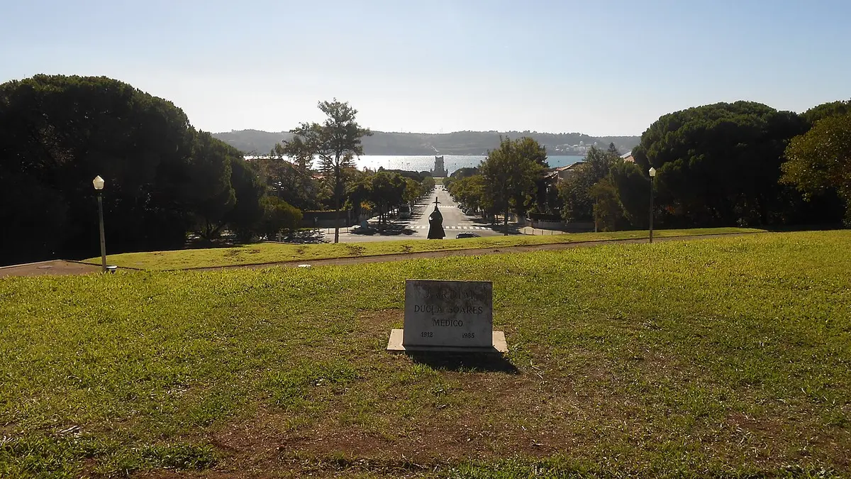 Relvado do Jardim Ducla Soares com placa de pedra e vista sobre a avenida até à Torre de Belém