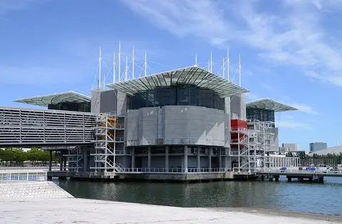 Edifício do Oceanário de Lisboa sobre a água, no Parque das Nações, em dia de céu azul