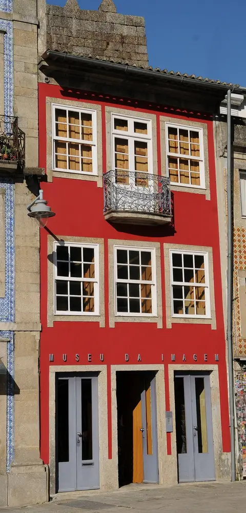 Fachada vermelha do Museu da Imagem, em Braga, com varanda de ferro e portas no piso térreo