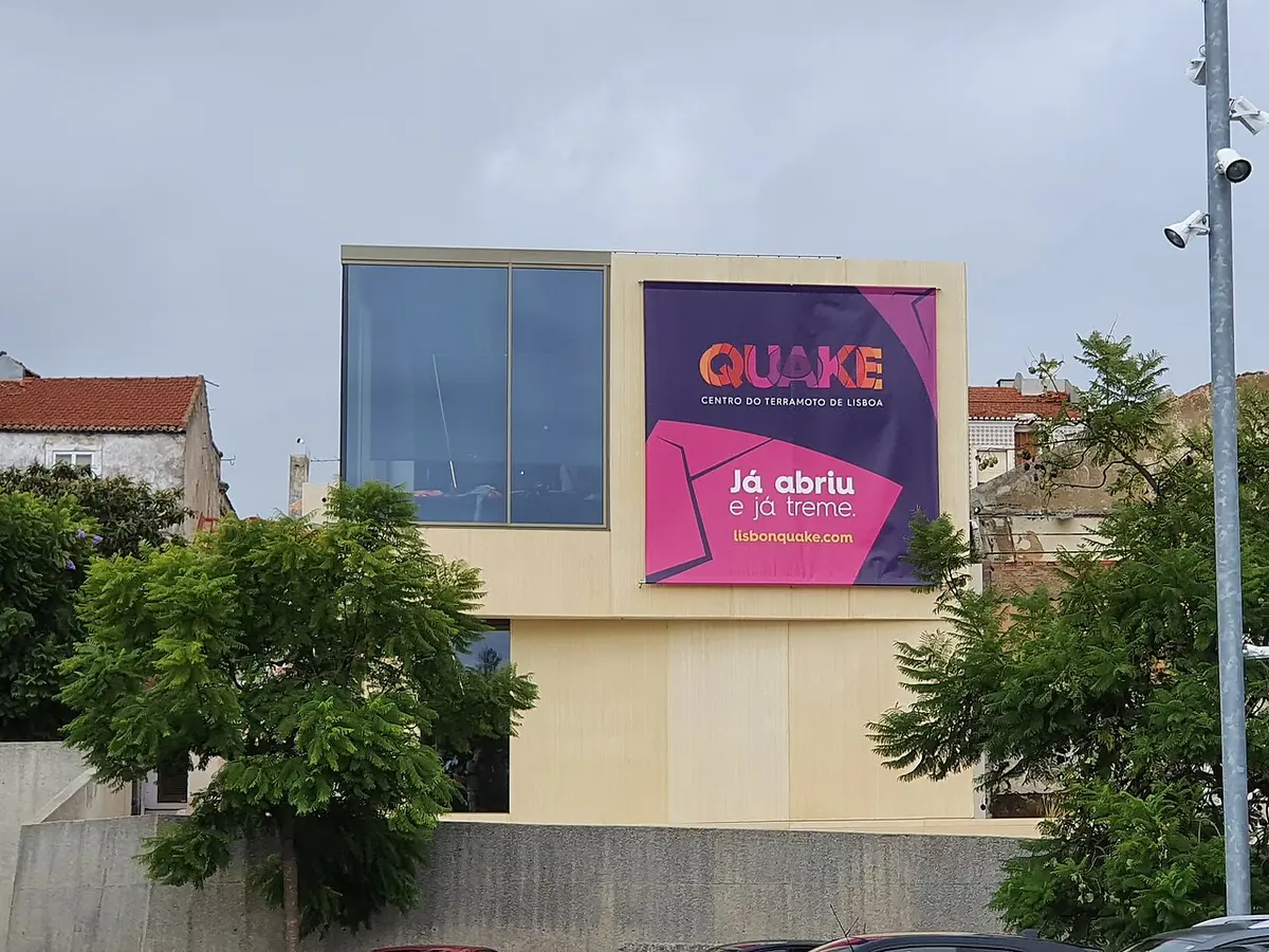 Fachada do Quake - Centro do Terramoto de Lisboa com grande cartaz cor-de-rosa e roxo