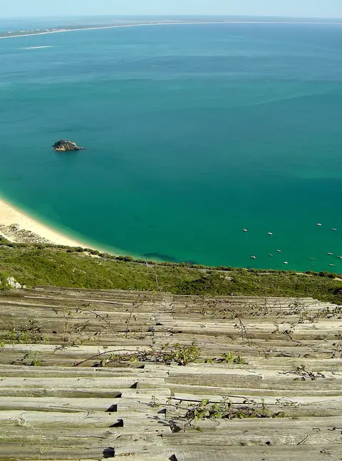 Vista do alto da Serra da Arrábida sobre o mar turquesa e a praia do Portinho da Arrábida