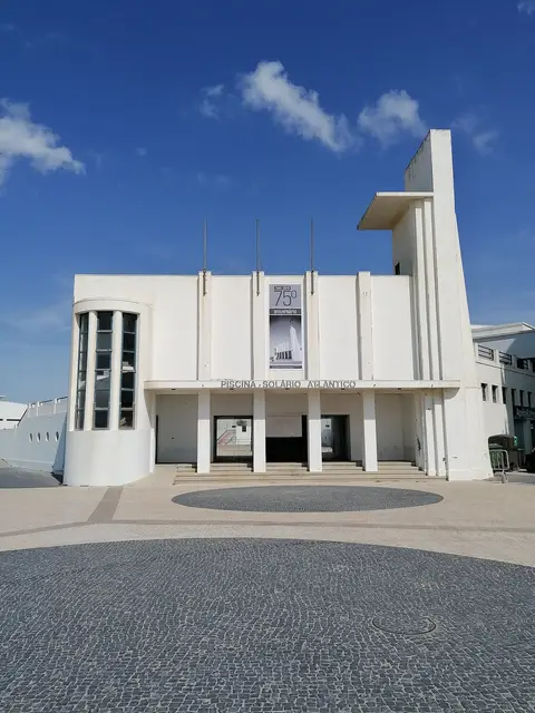 Fachada branca modernista da Piscina Solário Atlântico com calçada portuguesa em frente