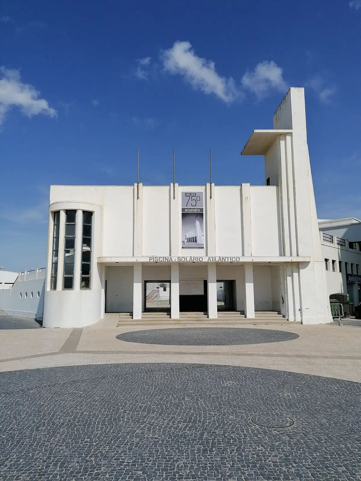 Fachada branca modernista da Piscina Solário Atlântico com calçada portuguesa em frente
